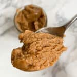 Spoonful of granola butter over jar of granola butter.