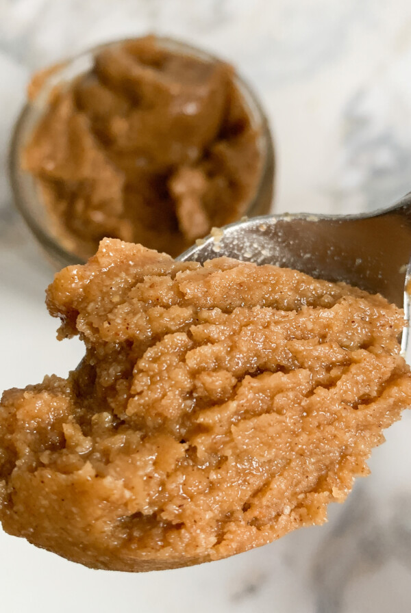 Spoonful of granola butter over jar of granola butter.