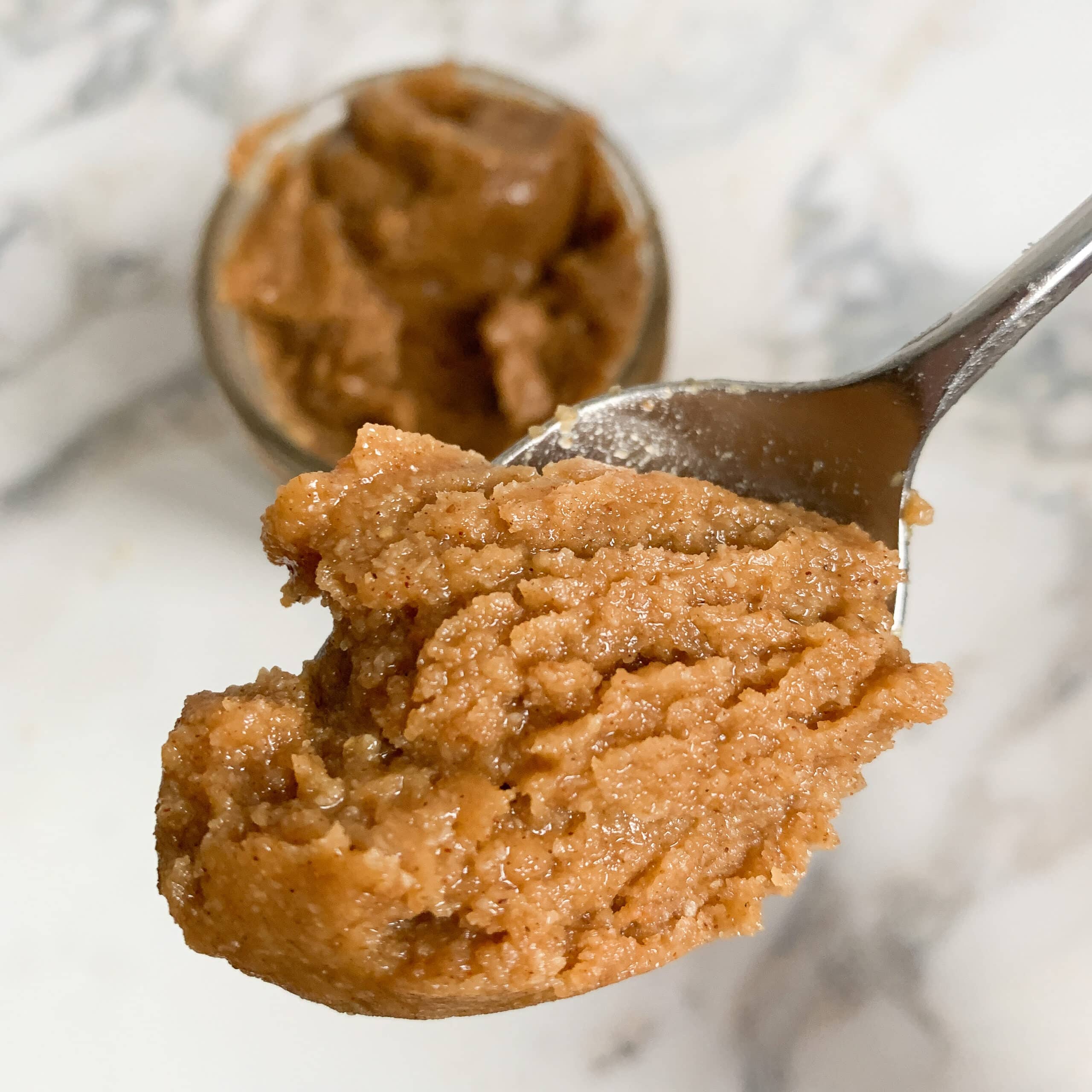 Spoonful of granola butter over jar of granola butter.