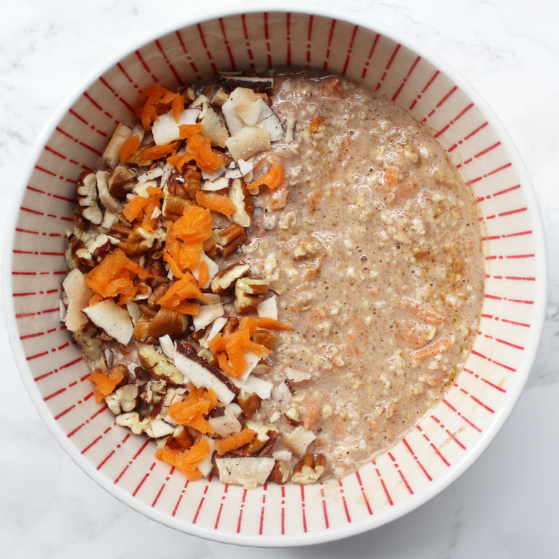 Carrot Cake Overnight Oats in a white and orange bowl. carrot, pecans and coconut on top.