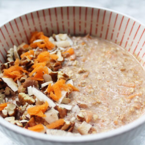 Side view of carrot cake overnight oats topped with shredded carrot, pecans and coconut.