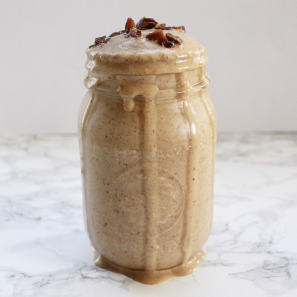 Banana date smoothie in a jar, dripping down the sides, with cut up date on top