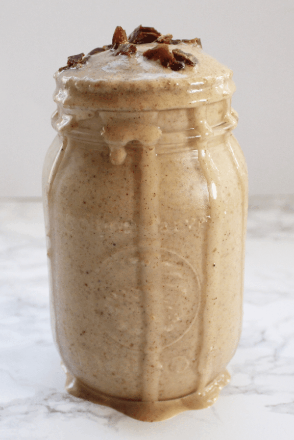 Banana date smoothie in a jar, dripping down the sides, with cut up date on top