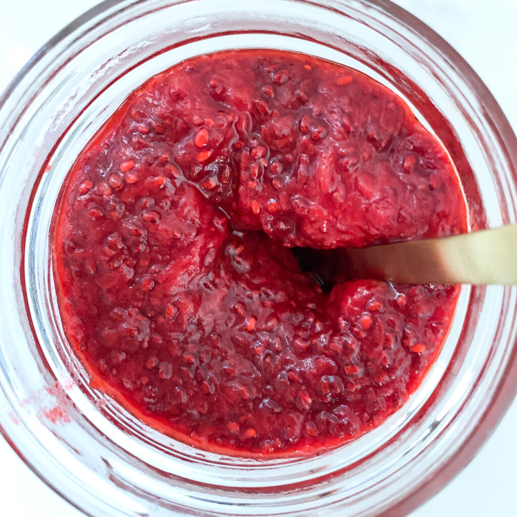 Bird's-eye view of strawberry jam with a gold coloured spoon in it