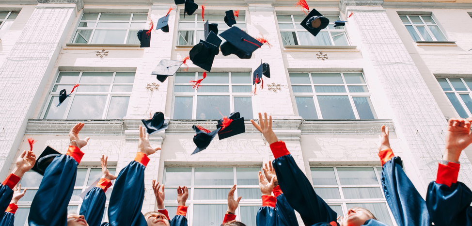 Group of kids jumping in the air throwing their graduation caps