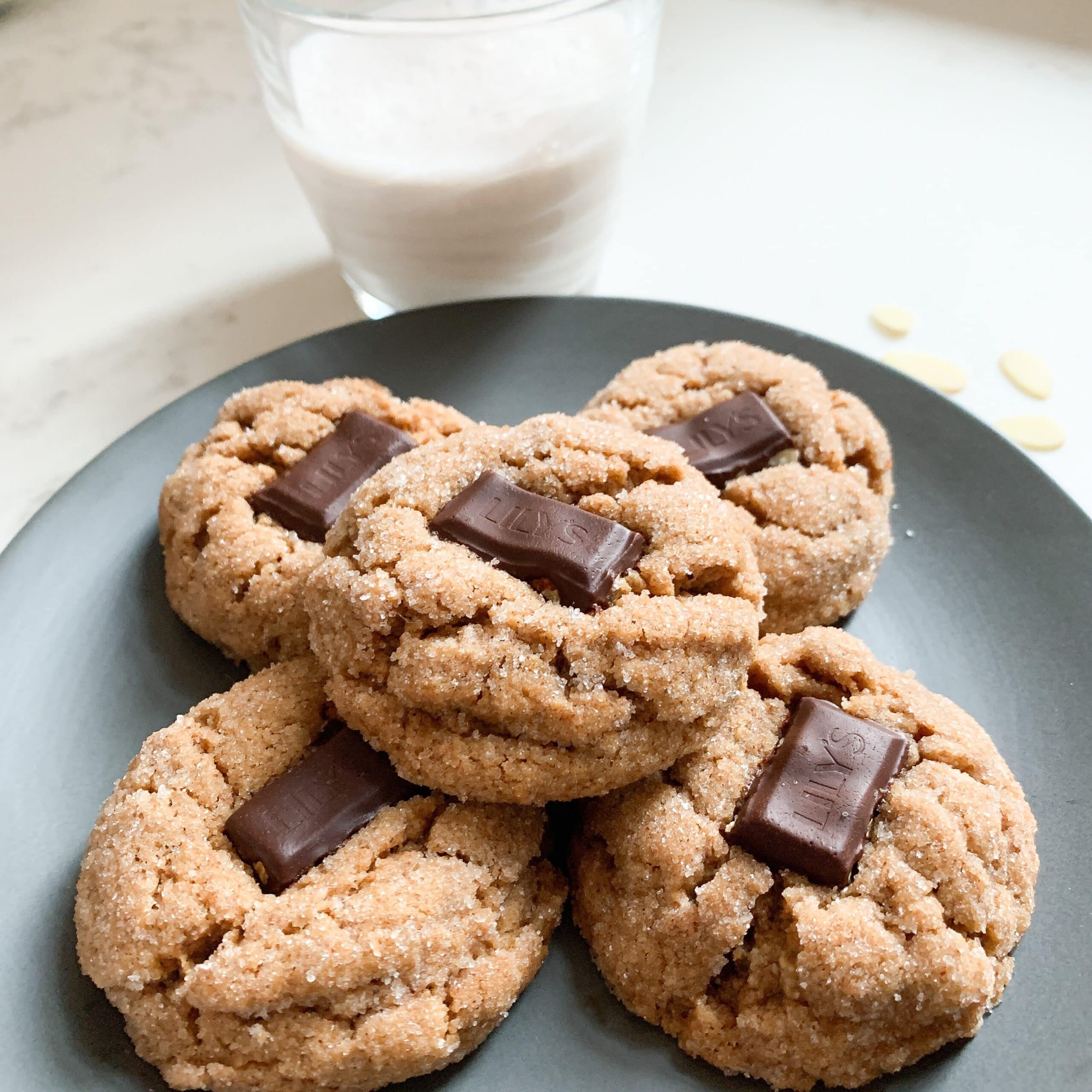 Cookies with chocolate in middle on blue plate with glass of milk.