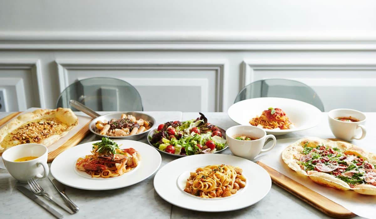 Food options including pasta, salad, pizza and soup on marble tabletop.