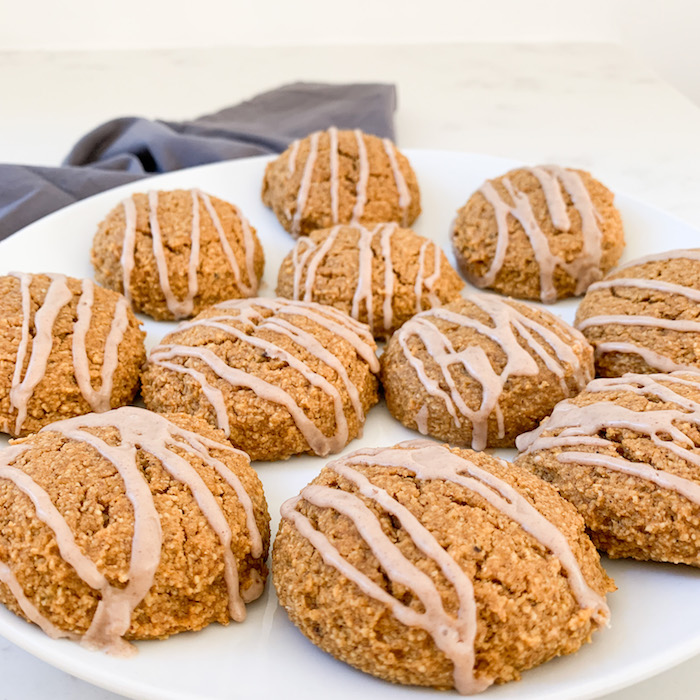 Gluten-free pumpkin cookies with cinnamon drizzle on white plate with blue napkin in the background.