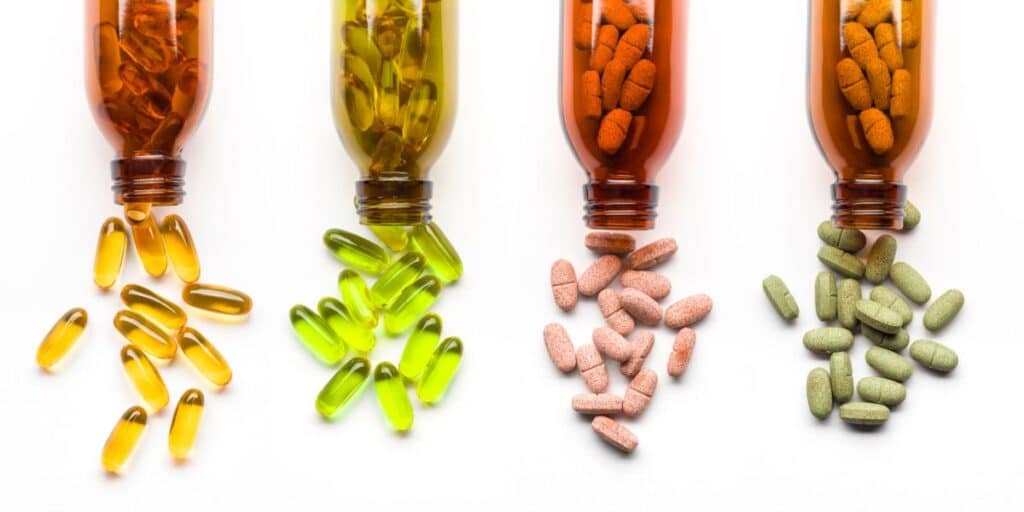 Four supplement bottles on their side with pills coming out of them.