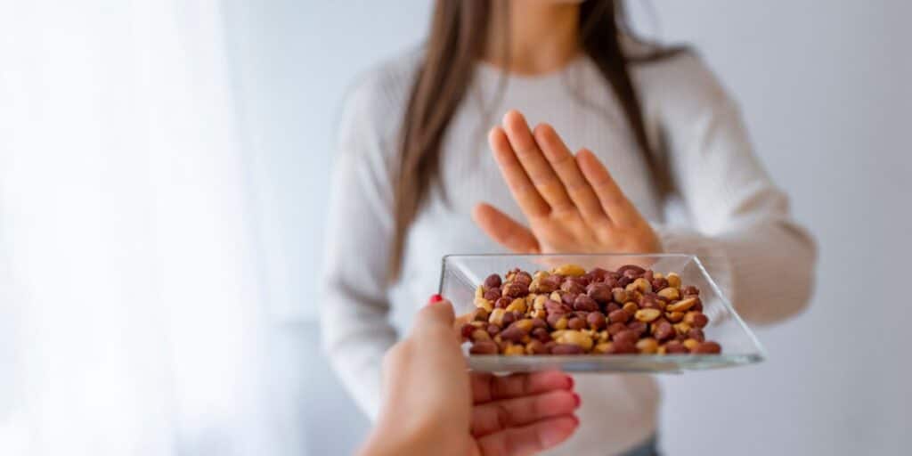 Female refusing a plate of peanuts with hand up.