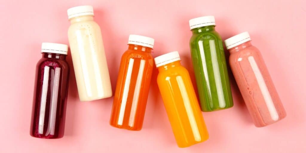 Colorful bottled drinks on pink background.