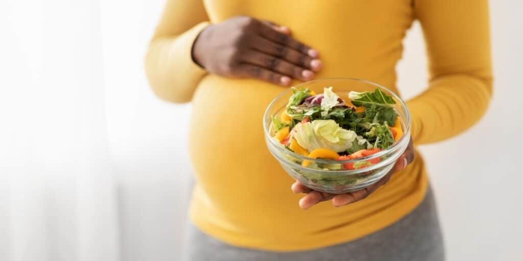 Pregnant woman holding a salad.