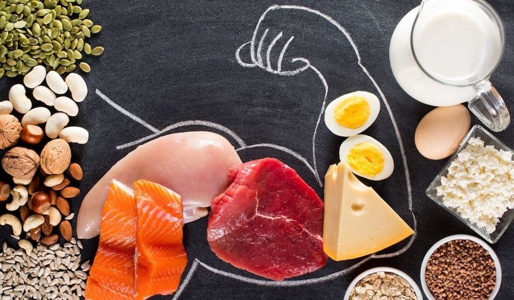 High protein foods on a chalkboard with a muscle drawn on it.