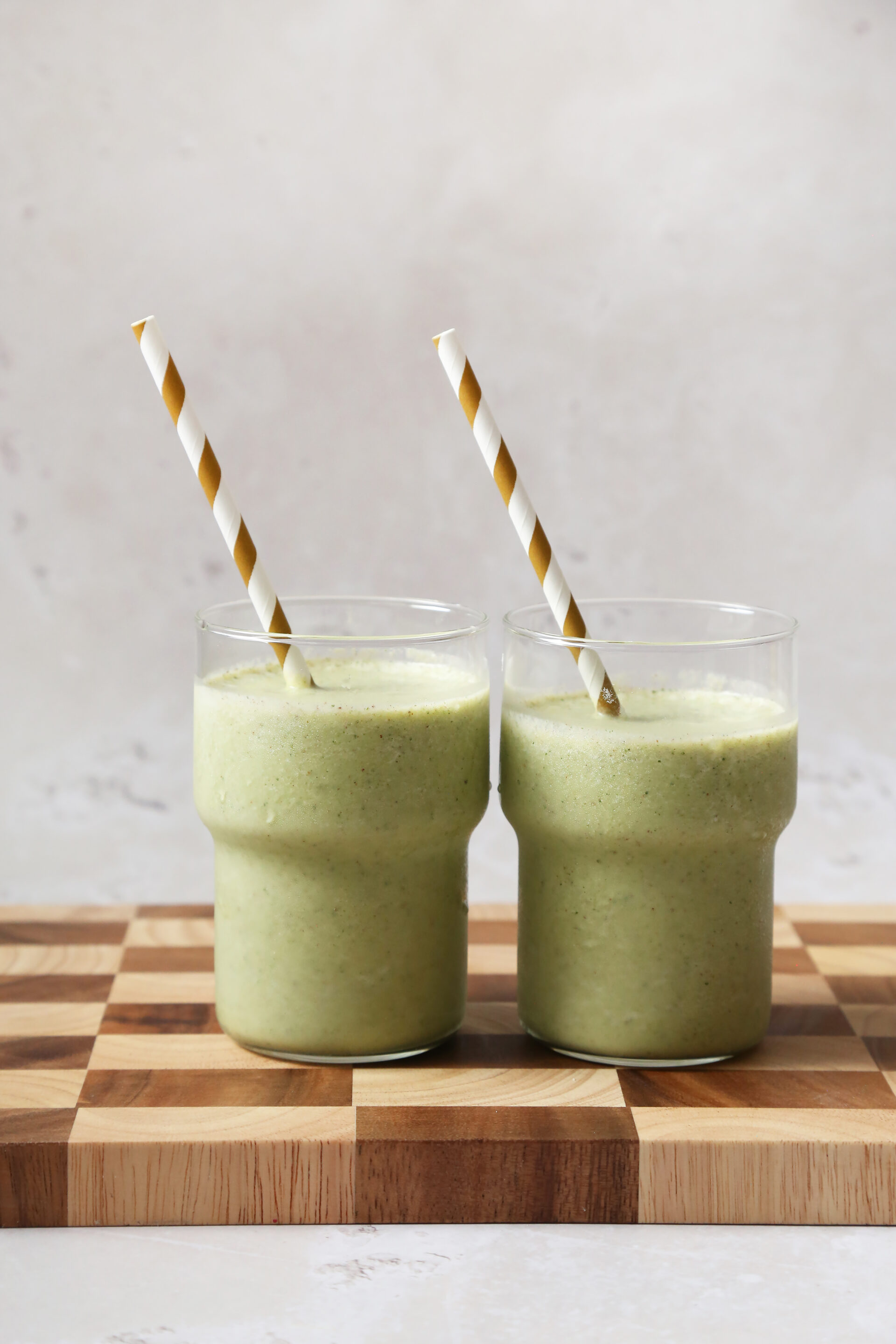 Two green smoothies with striped straws.