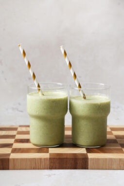 Two green smoothies with striped straws.