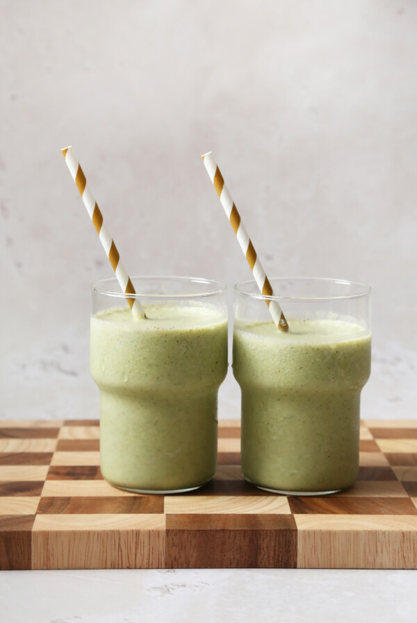 Two green smoothies with striped straws.