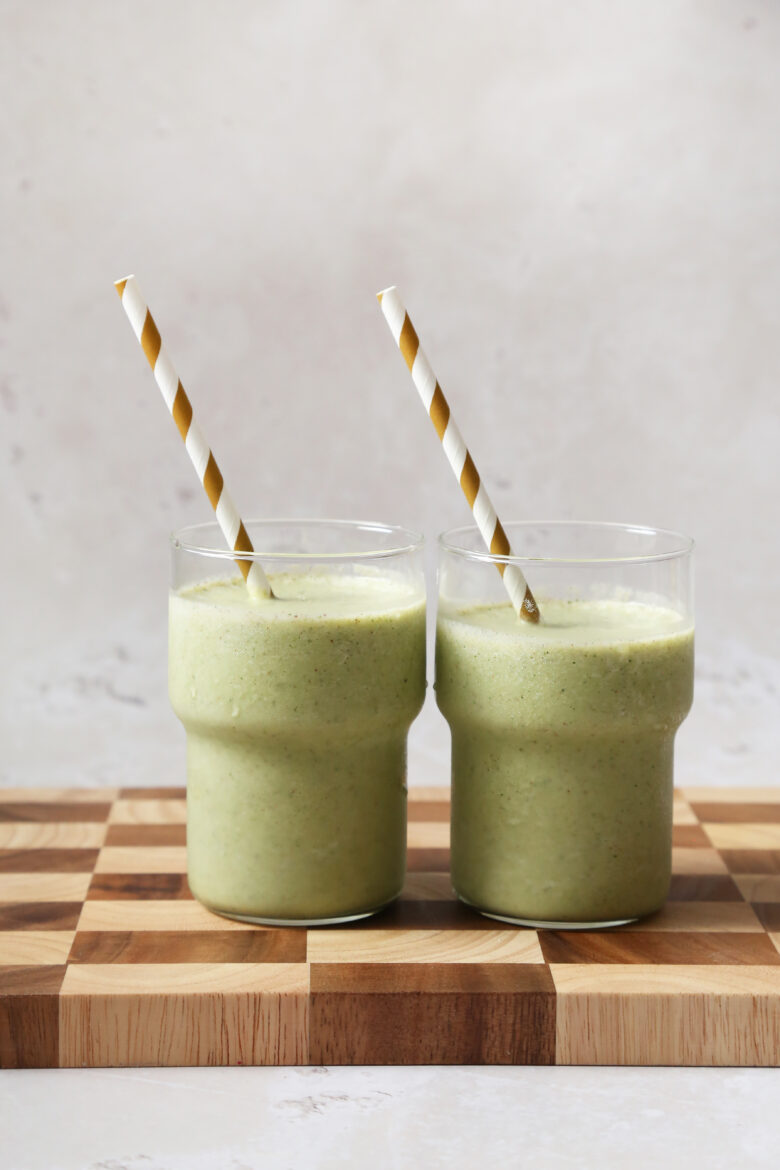 Two green smoothies with striped straws.