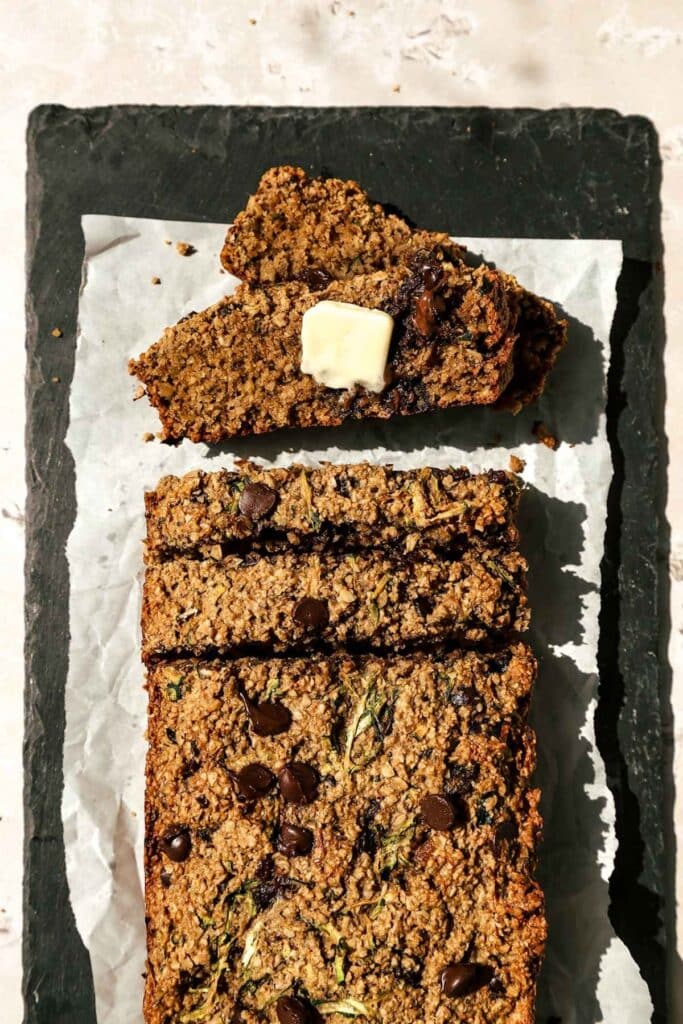 Overhead view of zucchini oatmeal bread sliced with butter on one piece.
