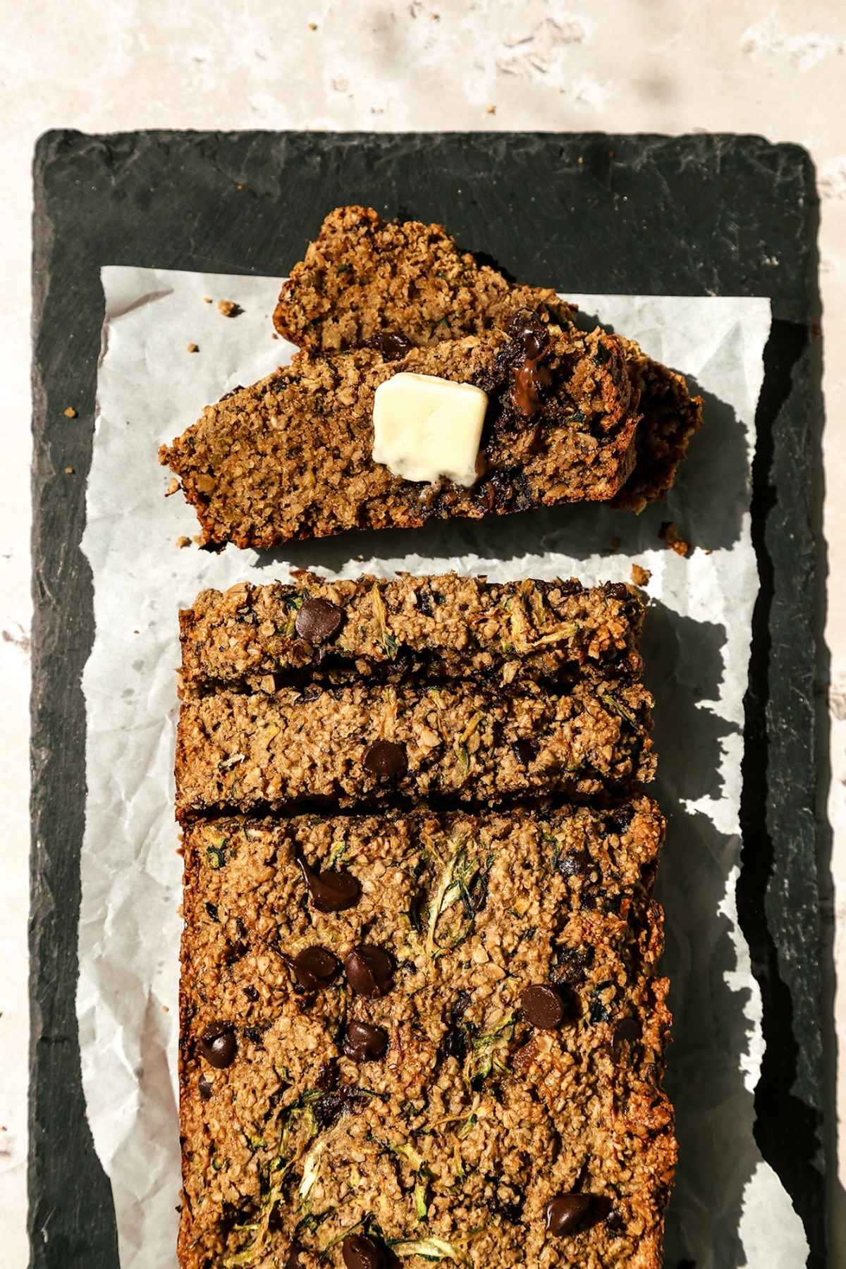 Overhead view of zucchini oatmeal bread sliced with butter on one piece.
