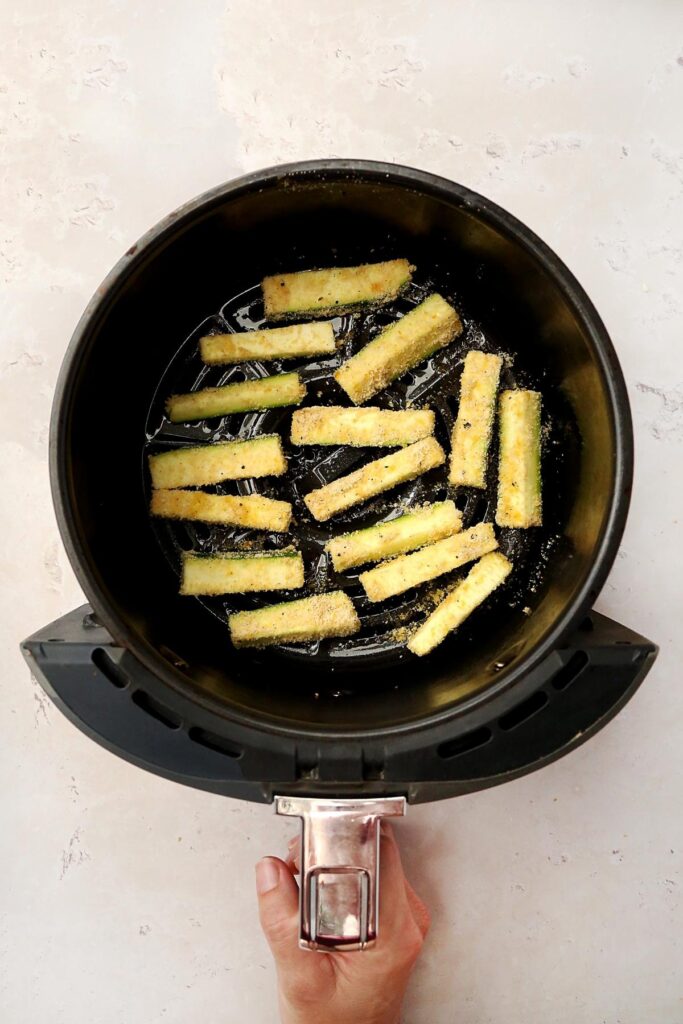 Zucchini fries in an air fryer basket.