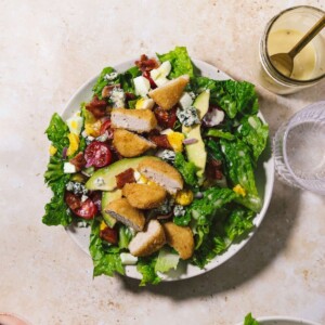 Overhead view of chicken nugget cobb salad in a bowl with dressing on the side.