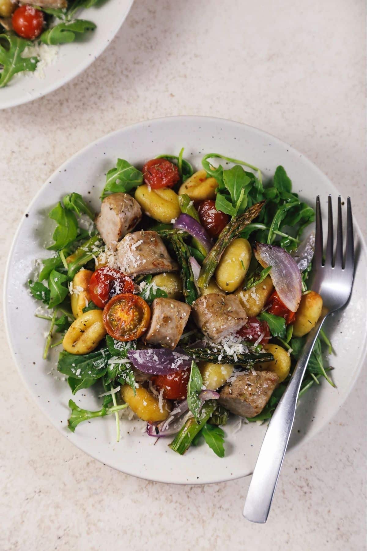 Overhead view of sheet pan gnocchi with sausage and vegetables in a bowl, close up