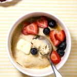 Pancake bowl with berries and melting butter on a yellow stripped background.