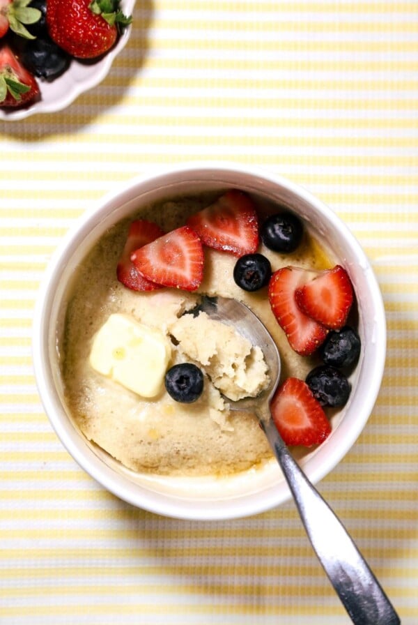 Pancake bowl with berries and melting butter on a yellow stripped background.