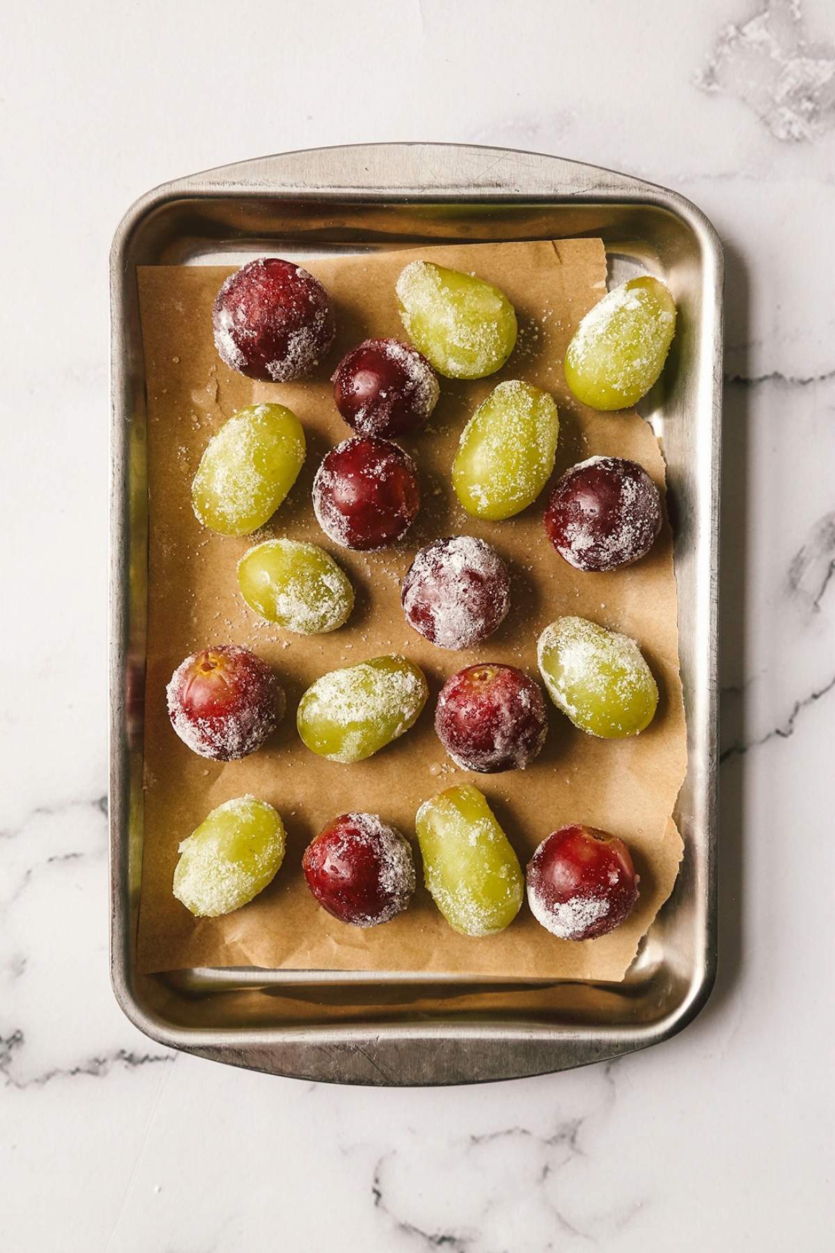 Overhead shot of green and red grapes on a cookie sheet with parchment.