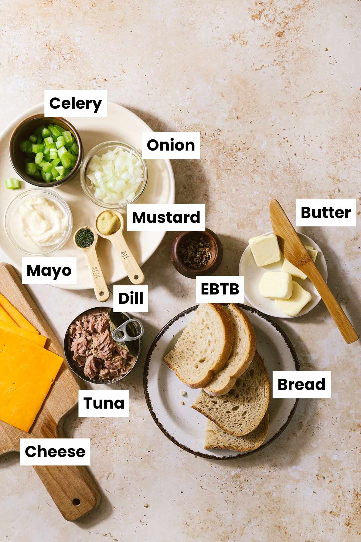 Overhead shot of air fryer tuna melt ingredients, including, celery, onion, mustard, dill, everything but the bagel seasoning, butter, tuna, cheese, and bread.