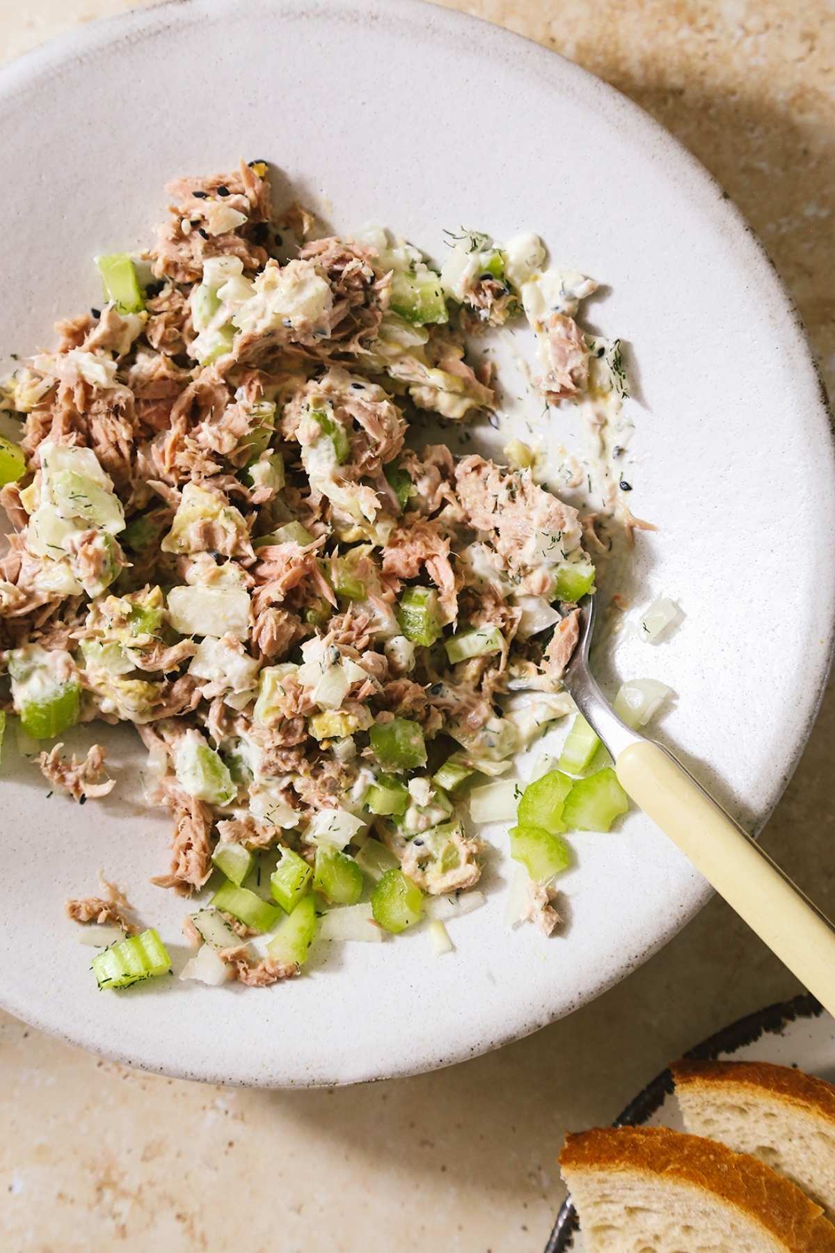 Tuna melt sandwich ingredients mixed together in a white bowl.